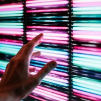 person s hand touching blue and pink led panel